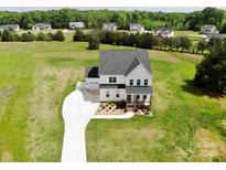 Stunning aerial view of white farmhouse, long driveway and expansive green yard, showcasing its serene setting at 623 Plowshare Way, Clover, SC 29710