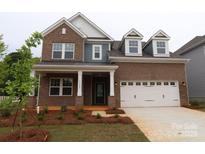 Charming two-story brick home featuring a white garage door and a beautifully landscaped front yard at 11105 Lochmere Rd, Charlotte, NC 28278