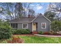 Charming single-story home featuring a gray exterior, yellow front door, and well-maintained landscaping at 1416 Woodland Dr, Charlotte, NC 28205