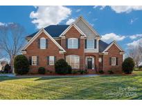 Stately brick home featuring a manicured lawn, dormers, and black shutters at 8018 Cotton St, Harrisburg, NC 28075