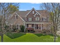 Charming two-story home with stone and siding exterior, a covered front porch, and a well-maintained lawn at 10823 Caverly Ct, Huntersville, NC 28078