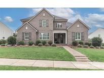 Beautiful two-story home with manicured lawn, charming shutters, and a brick walkway leading to the front entrance at 13306 Old Store Rd, Huntersville, NC 28078