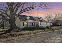 Charming home featuring a front porch, dormer windows, and a well-maintained lawn at sunset at 406 E 29Th St, Kannapolis, NC 28083