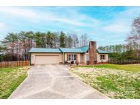 Charming home features a metal roof, attached garage, and well-maintained lawn at 6142 Gold Creek Estate Dr, Hickory, NC 28601