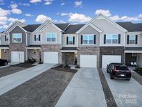 Charming townhome exteriors featuring brick accents, individual garages, and well-maintained landscaping at 7006 Everly Commons Ln, Tega Cay, SC 29708
