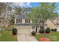 Charming two-story home with a well-manicured lawn, mature trees, and an attached two-car garage at 8932 Raven Park Dr, Charlotte, NC 28216