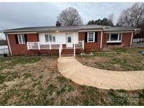 Charming brick home featuring a metal roof, white trim, and inviting walkway leading to the front door at 920 Oakridge Farm Hwy, Mooresville, NC 28115
