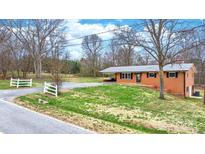 Charming brick home with metal roof, green lawn, driveway and white picket fence at 104 Pop Davis Rd, Taylorsville, NC 28681