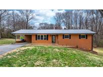 Charming brick home featuring a metal roof, black shutters, well-kept lawn and convenient carport at 104 Pop Davis Rd, Taylorsville, NC 28681