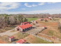 Aerial view showcases equestrian property featuring barns, paddocks, and open fields at 262 Tuckers Grove Rd, Statesville, NC 28625