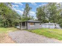 Charming single-story home with a gravel driveway, covered front porch, and well-maintained landscaping at 5825 Greene St, Charlotte, NC 28269