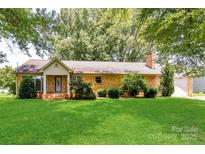 Charming brick home with lush green lawn and mature trees offering a picturesque setting at 7770 Sherrills Ford Rd, Sherrills Ford, NC 28673