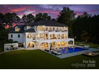 Expansive backyard featuring a pool with water features, lounge areas, a fire pit, and a covered outdoor living space at 16439 Jetton Rd, Cornelius, NC 28031