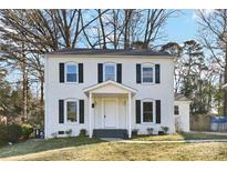 Charming two-story home featuring a white brick facade, black shutters, and a welcoming front porch at 5717 Ruth Dr, Charlotte, NC 28215