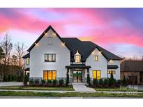 Stunning exterior of a two-story home with stone accents, manicured landscaping, and a beautiful sunset backdrop at 5834 Five Knolls Dr, Charlotte, NC 28226