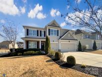 Two-story home featuring a two-car garage, well-manicured lawn, and manicured landscaping at 11123 River Oaks Nw Dr, Concord, NC 28027