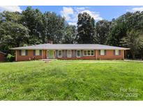 Ranch-style brick home with large front yard and mature trees offers classic charm and curb appeal at 1210 Brookwood Dr, Shelby, NC 28150
