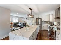 Modern kitchen with stainless steel appliances, marble counters, island, and open view to the living room at 307 Farmhurst Dr, Charlotte, NC 28217