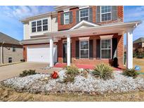 Charming two-story brick home featuring a well-manicured lawn, covered porch, and attached two-car garage at 815 Oak Embers Se Dr, Concord, NC 28025