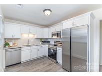 Updated kitchen featuring stainless steel appliances, white cabinets, granite countertops, and modern gray backsplash at 8322 Knights Bridge Rd, Charlotte, NC 28210