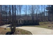 Charming single-story home with a long driveway and a welcoming front porch nestled amongst trees at 312 Sailwinds Rd, Mooresville, NC 28115