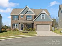 Charming two-story home with a brick facade, covered entrance, two-car garage, and well-maintained lawn at 5585 Zeeland Ln, Fort Mill, SC 29707