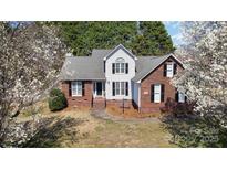 Charming two-story home with brick and white siding, black shutters, and mature trees in a landscaped yard at 919 42Nd Avenue Ne Ln, Hickory, NC 28601