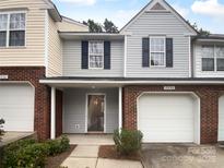 Charming townhome featuring a one-car garage and a welcoming front porch with landscaped bushes at 9930 Birch Knoll Ct, Charlotte, NC 28213