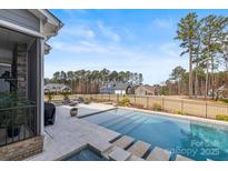 Beautiful backyard pool with stone patio, spa, lounge chairs, and view of the neighborhood at 107 Hillside Cove Ct, Mooresville, NC 28117