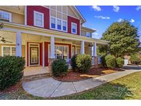 Inviting home featuring a charming front porch with stone accents and manicured landscaping at 137 Hunters Hill Dr, Statesville, NC 28677