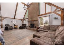 Spacious living room featuring a large brick fireplace, vaulted ceilings with wooden beams, and ample natural light at 360 Patience Dr, Concord, NC 28025