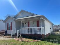 Charming home with a cozy front porch, white railings, and red shutters, creating an inviting curb appeal at 376 Brookgreen Nw Pl, Concord, NC 28027