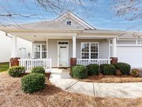 Charming one-story home featuring a cozy front porch, well-maintained landscaping, and an attached two-car garage at 415 Ridgely Green Dr, Pineville, NC 28134