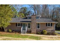 Inviting single-story home with a brick chimney, dormer windows, and a well-maintained front yard at 5615 Starkwood Dr, Charlotte, NC 28212