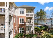 Lakefront condo featuring balconies, brick accents, and lush landscaping with beautiful lake views at 921 Northeast Dr # 26, Davidson, NC 28036