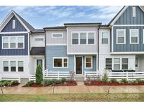 Charming two-story townhouse with a mix of blue and gray siding, a small landscaped front yard, and a white picket fence at 1270 Brawley School Rd # E, Mooresville, NC 28177