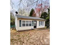 Cozy single-story home featuring light siding, a dark roof, dark shutters, and a tree-filled yard, offering a welcoming curb appeal at 133 Proctor St, Gastonia, NC 28052