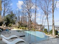 A luxurious pool and patio area overlooking a scenic lake offers ultimate relaxation at 20338 Christofle Dr, Cornelius, NC 28031