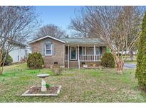 Charming brick home with landscaped front yard and a quaint covered porch entrance at 12 Roberta Rd, Concord, NC 28027