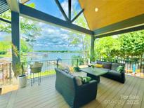 Relax on this covered patio featuring comfortable seating and stunning lake views, perfect for outdoor living and entertaining at 121 Kelly Point Ln, Mooresville, NC 28117