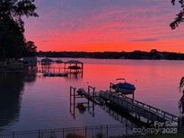 Stunning waterfront view with private boat docks beneath a vibrant pink and orange sunset, exuding tranquility at 121 Kelly Point Ln, Mooresville, NC 28117