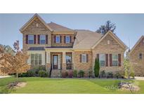 Charming two-story brick home with a well-manicured lawn and inviting front porch at 17809 Pawleys Plantation Ln, Charlotte, NC 28278