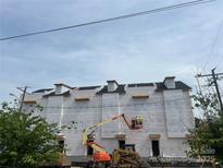 A building under construction with construction workers and equipment, under a blue sky at 3018 Casting St # 20, Charlotte, NC 28206
