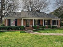 Charming brick home with a well-manicured lawn and covered front porch at 1030 Bolling Rd, Charlotte, NC 28207