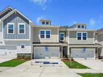 New construction townhomes boast craftsman exteriors, attached garages, and manicured lawns under a bright, sunny sky at 109 Alluvium Ln, Waxhaw, NC 28173