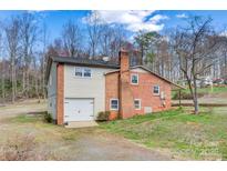 Side view of a brick two-story home featuring an attached one-car garage and a well-maintained lawn at 1740 Young Dr, Conover, NC 28613