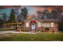 Charming single-story brick home with a covered porch, landscaped front yard, and a carport on the side at 198 33Rd Nw St, Hickory, NC 28601