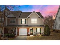 Inviting townhouse featuring a one-car garage, charming front porch, and lush landscaping at 2592 Brackley Nw Pl, Concord, NC 28027