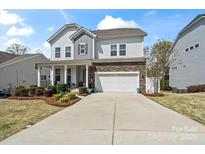 Charming two-story home with a stone accent, landscaped yard, covered porch, and an attached two-car garage at 7200 Irongate Dr, Indian Land, SC 29707