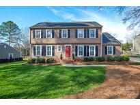 Charming two-story home featuring a red front door, well-manicured lawn, and classic black shutters at 916 Somersby Ln, Matthews, NC 28105